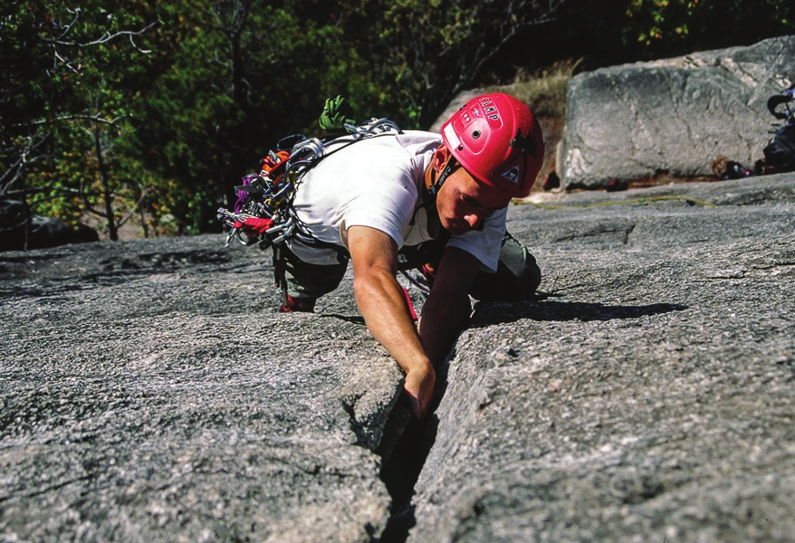 A climber jamming a hand into a granite crack on a low-angle slab
