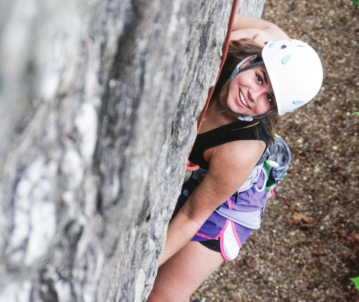 A climber on a steep featured face, looking down towards the camera