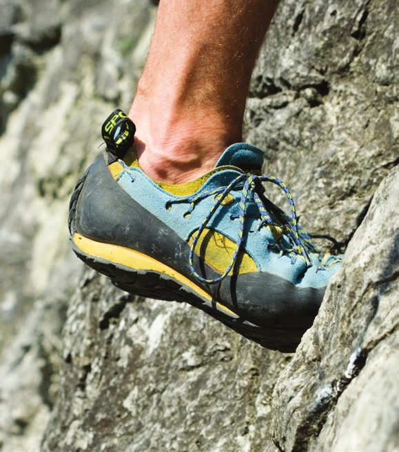 A climbing shoe edging on a small hold with the big toe, heel turned slightly outward