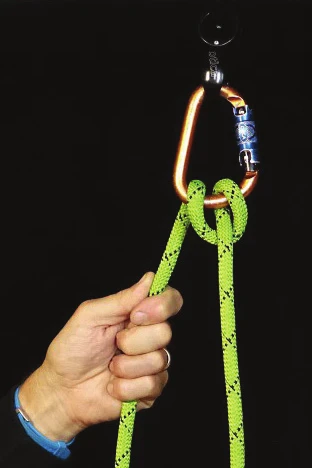 An Italian hitch on a large locking carabiner, with a hand controlling the brake strand