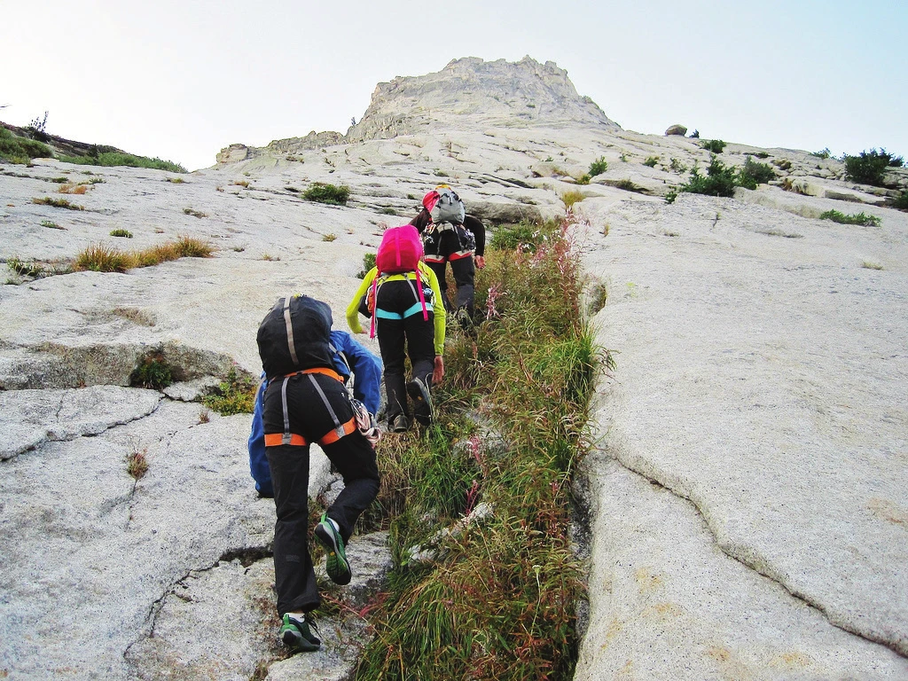 Un groupe progressant sur une dalle de granite peu inclinée en approche d’un site d’escalade